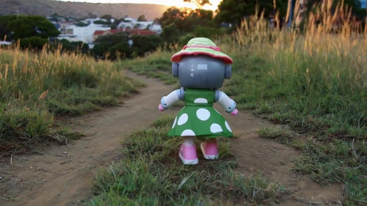 一个穿着绿色裙子和太阳帽的玩具机器人在南非约翰内斯堡美丽的日落时分愉快地散步。