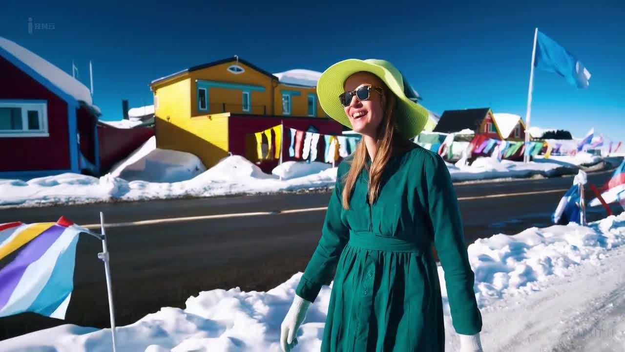 一个穿着绿色裙子和太阳帽的女人在南极洲举行的一场多彩节日中愉快地散步。