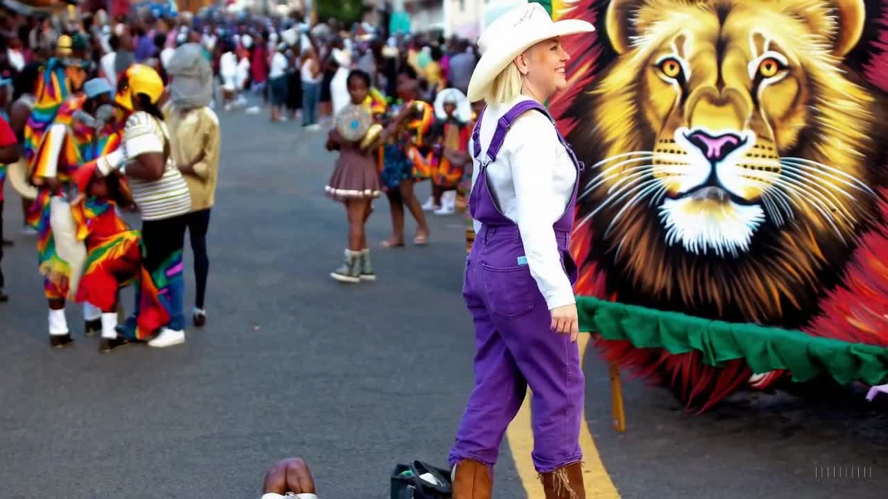 一个穿着紫色工装裤和牛仔靴的女人在南非约翰内斯堡举行的一场多彩节日中愉快地散步。