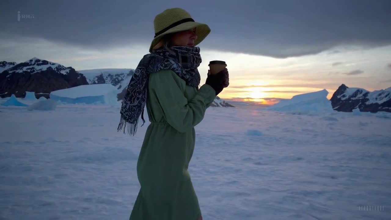 一个穿着绿色裙子和太阳帽的女人在南极洲美丽的日落时分愉快地散步。