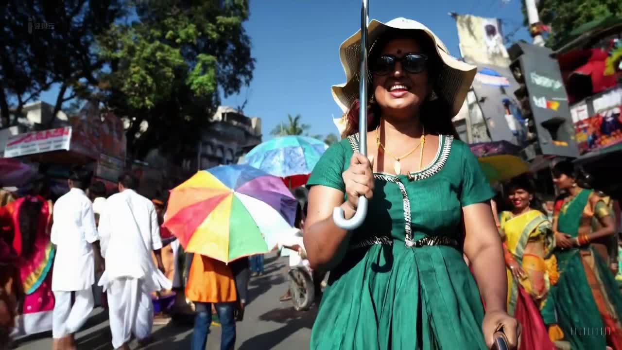一个穿着绿色裙子和太阳帽的女人在印度孟买举行的一场多彩节日中愉快地散步。