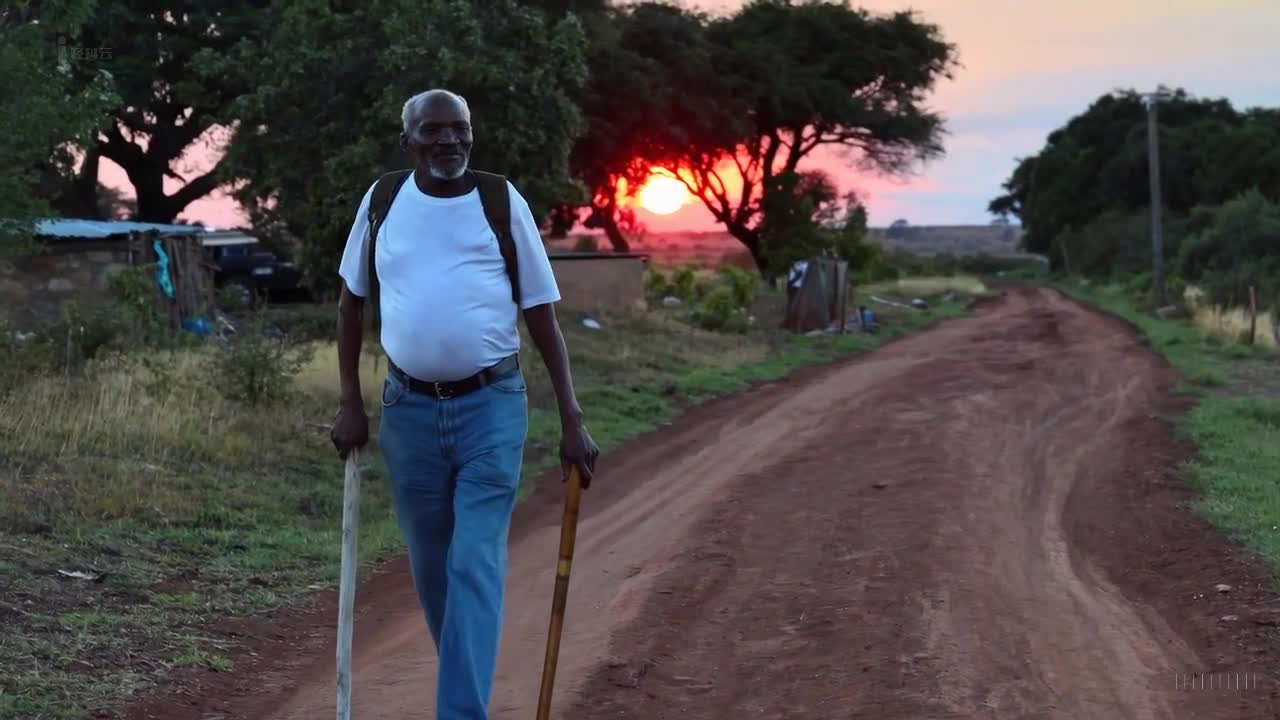 一个穿着蓝色牛仔裤和白色T恤的老人在南非约翰内斯堡美丽的日落时分。